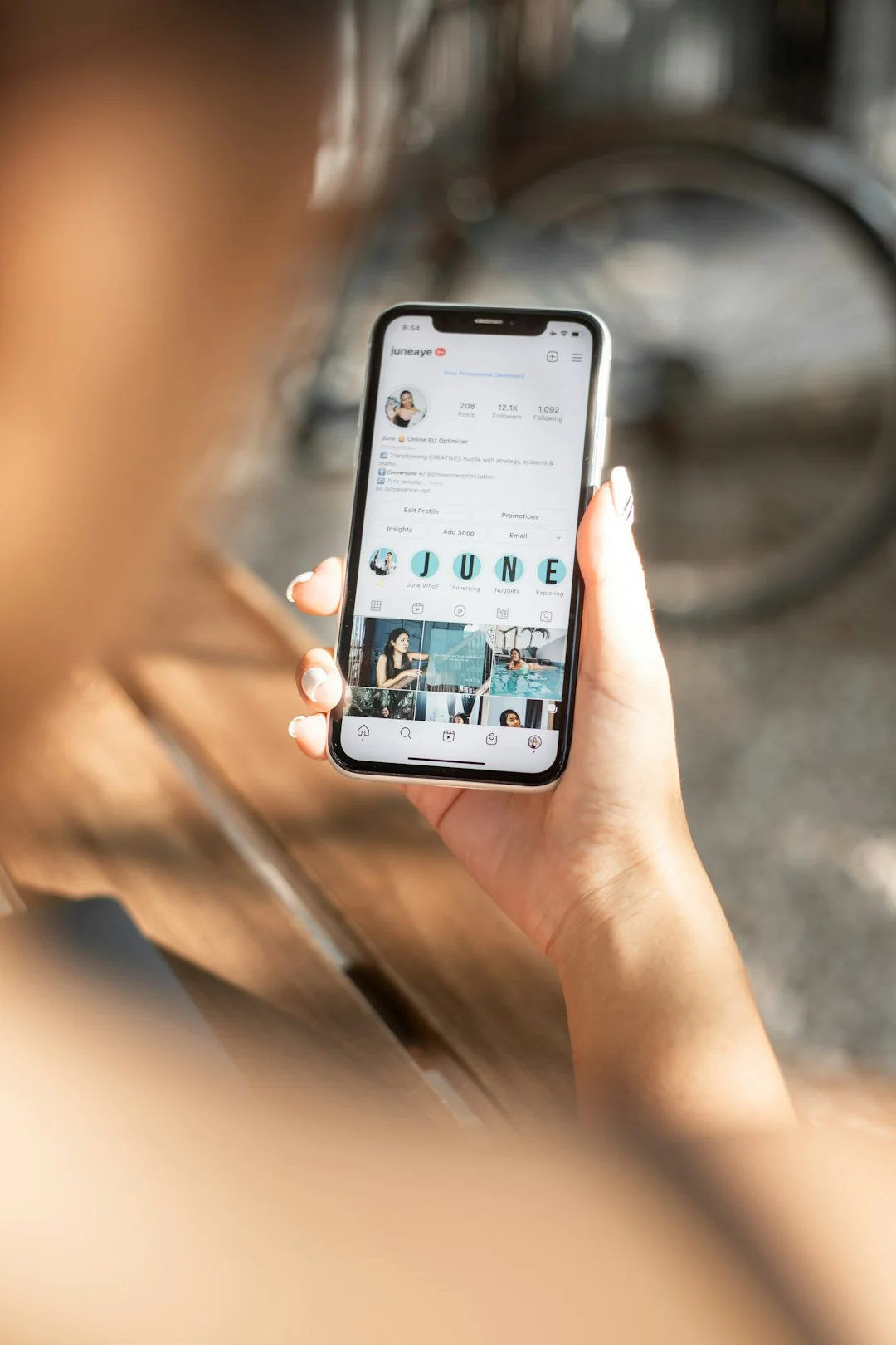 Main tenant un smartphone avec l’application e-mail ouverte, entouré de livres et d’un ordinateur portable.
